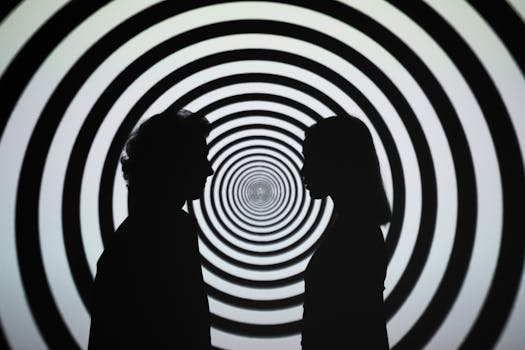 Silhouette of people facing each other with a hypnotic spiral background, creating an optical illusion.